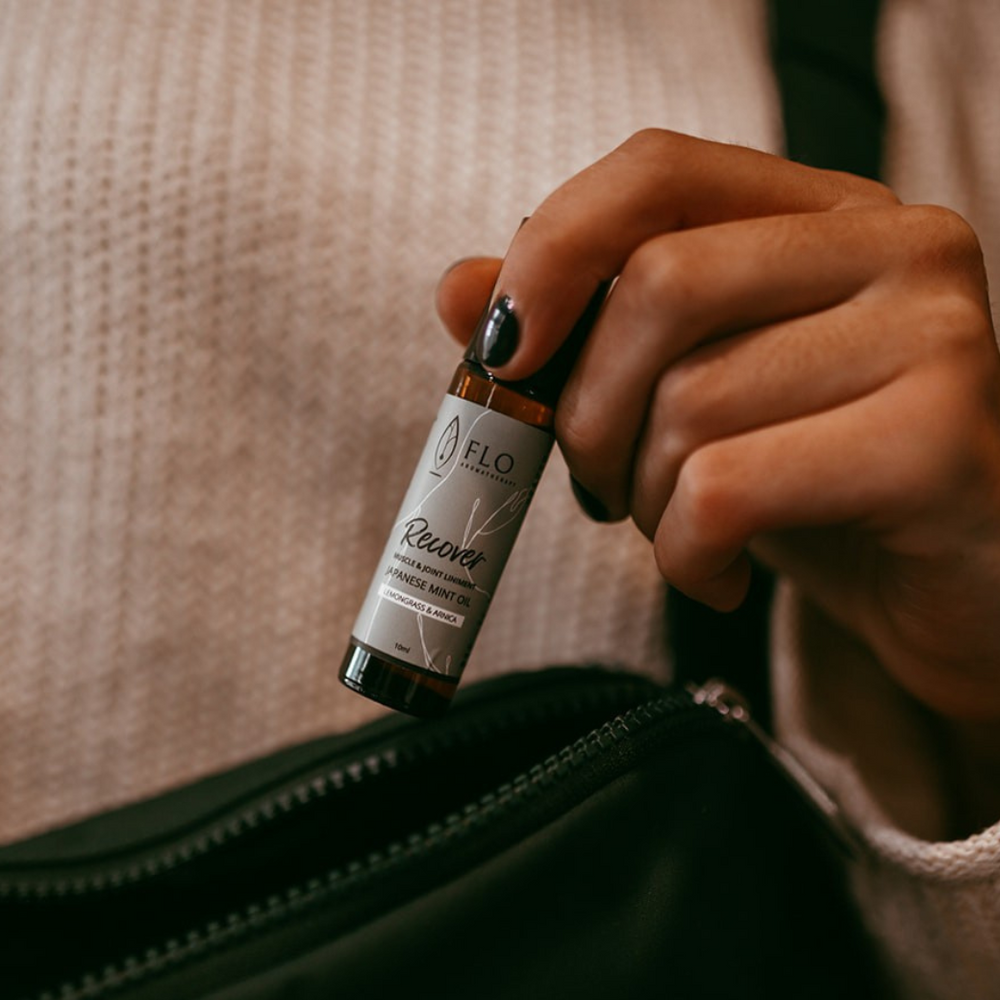 Hand placing Recovery Liniment Roll-On into a purse for easy on-the-go use.
