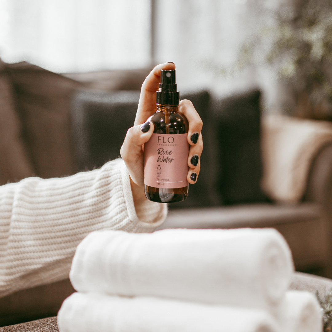 Hand spraying Rose Water mist onto fresh towels for linen refresh.